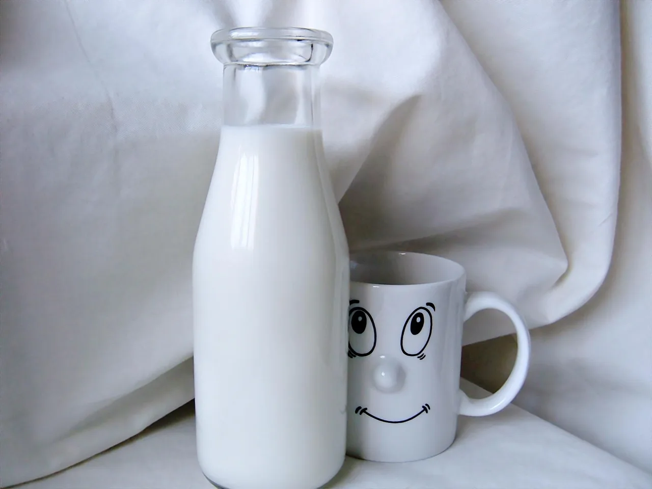 Un bicchiere di latte su un tavolo accanto a un libro, simbolo di relax serale prima di dormire.